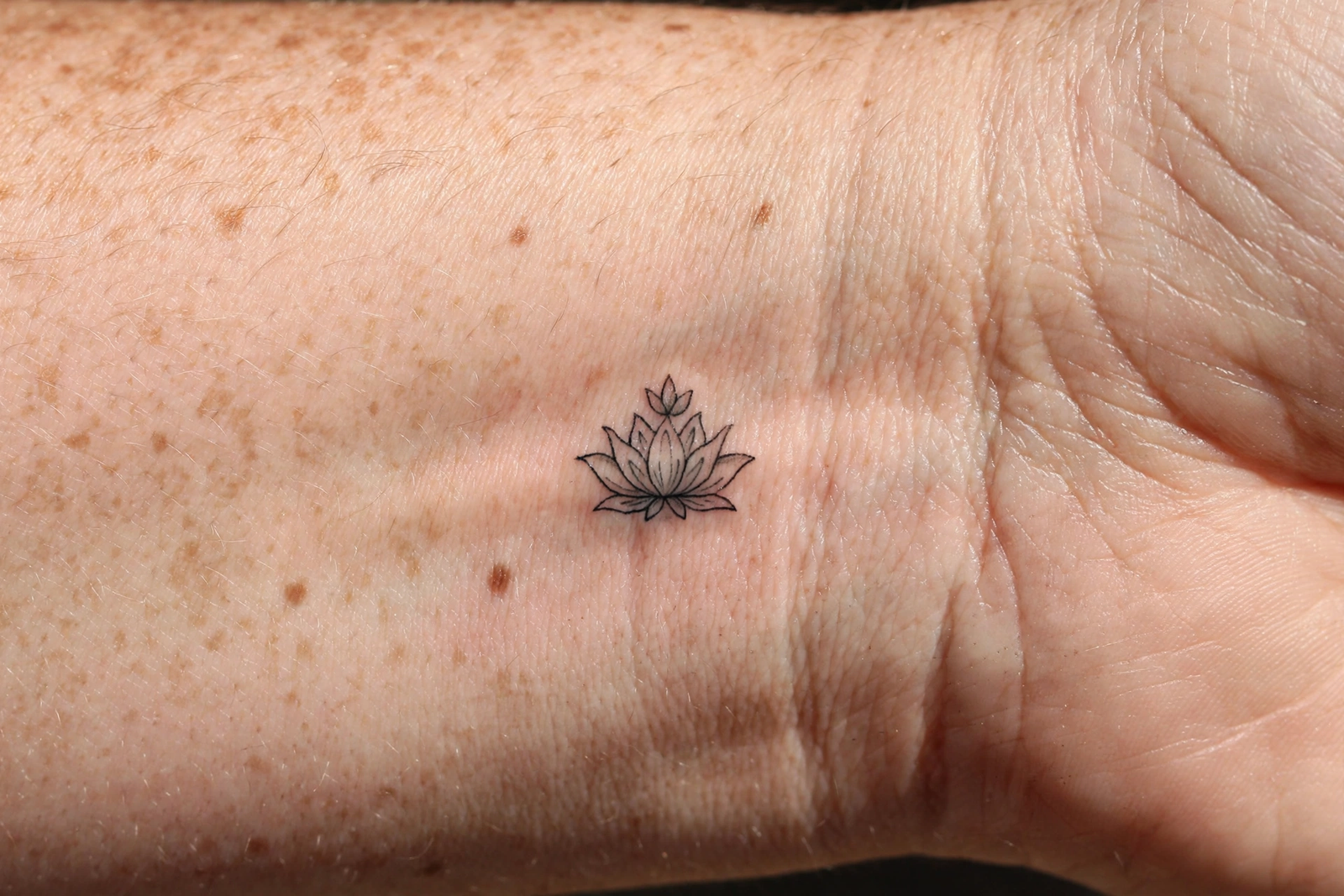 Small lotus tattoo on an inner wrist